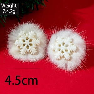 Close-up of white snowflake earrings with fluffy fur balls on festive red background