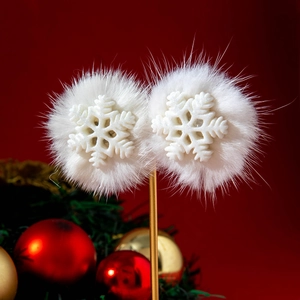 Detailed view of white pompom snowflake earrings over a festive red and green background