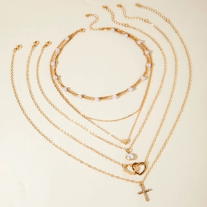 Ensemble de colliers superposés dorés avec perles, cœurs et pendentif croix