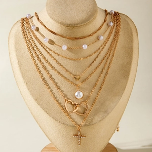 Collier multi-rangs doré avec perles, pendentifs cœur et croix en strass sur présentoir