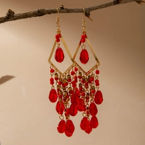 Detail of bohemian red beaded tassel earrings hanging on branch with gold accents