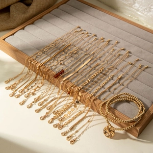 Stackable gold beaded bracelet and coin pendant necklace set on a velvet jewelry tray