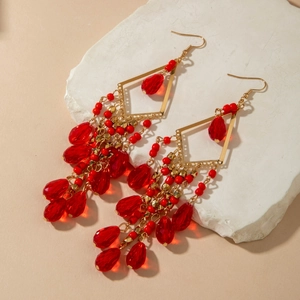 Macro shot of bohemian red glass bead tassel earrings on white stone display