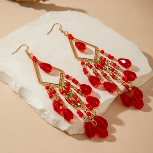Detail of bohemian red beaded tassel earrings with gold diamond-shaped metal frames