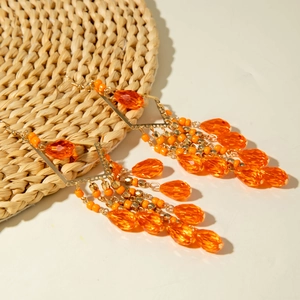 Detail of bohemian long tassel earrings with orange beads and teardrop crystals
