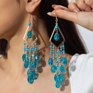 Detail of bohemian long tassel earrings with blue beads and golden metal frame