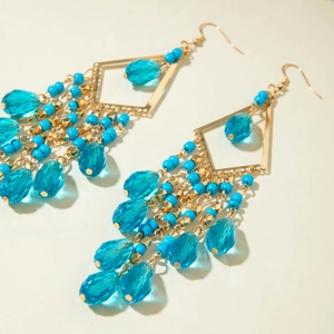 Detail of bohemian drop earrings with blue glass beads and golden geometric tassels