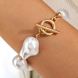 Close-up of baroque irregular pearl necklace featuring a gold OT toggle clasp detail