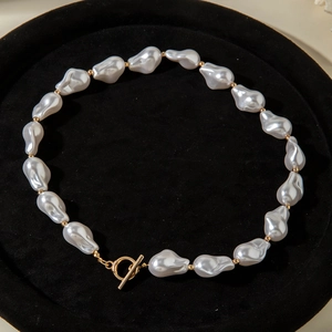 Detailed view of Baroque pearls with golden spacers and a toggle clasp on a black tray