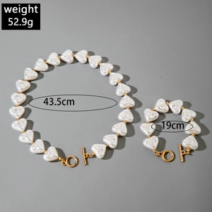 Detailed view of heart-shaped pearl necklace and bracelet set with golden OT toggle clasp