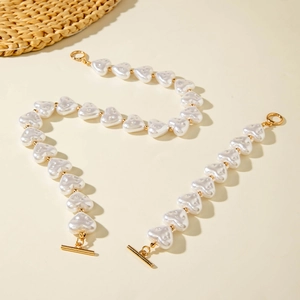 Detail of heart-shaped faux pearl necklace and bracelet set with golden OT toggle clasp