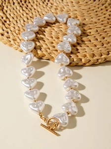 Macro detail of heart-shaped pearls and golden toggle clasp on an elegant necklace