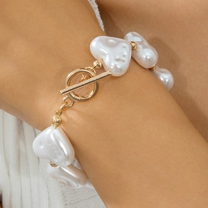 Close-up of heart-shaped pearl bracelet featuring a gold OT toggle clasp on a wrist