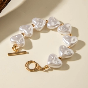 Detailed view of heart-shaped pearl bracelet with golden toggle clasp and beads