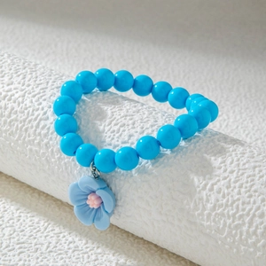 Détail d'un bracelet en perles bleu vif orné d'un pendentif en forme de fleur de camélia 3D