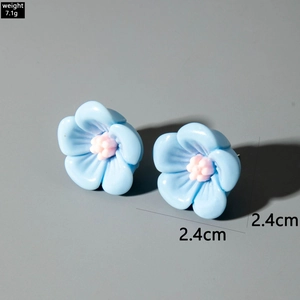 Détail de boucles d'oreilles camélia en résine bleue avec pistil rose et taille 2,4cm