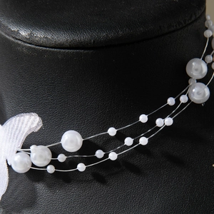 Three-layer butterfly pearl necklace with white round beads on a black neck display