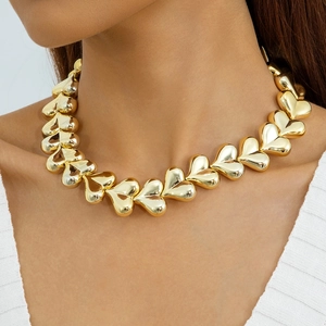 Close-up of a chunky polished golden heart link necklace worn by a fashion model