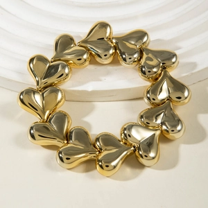 Detailed view of glossy golden heart-shaped linked bracelet on a white display pedestal