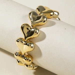 Macro detail of high-shine gold heart-shaped bead chain wrap around a cream pedestal