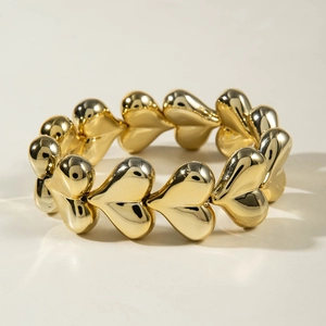 Detailed view of a shiny gold-plated heart-shaped chain bracelet on neutral background