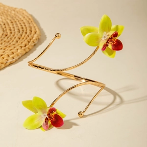 Detailaufnahme einer goldenen Spiral-Armspange mit detaillierten gelben Orchideen