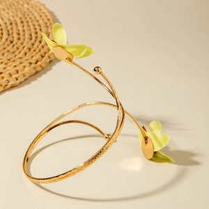 Detailansicht eines goldenen Spiral-Armreifs mit strukturiertem Metall und gelben Blumen