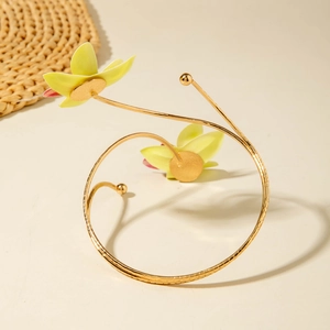 Goldener Spiral-Armreif mit zwei realistischen gelben Stoffblumen auf weißem Untergrund