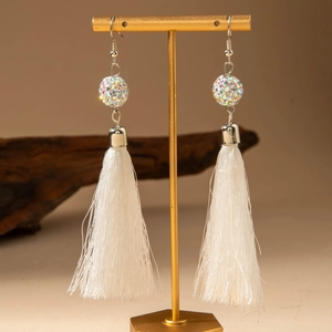 Détail de longues boucles d'oreilles à pampilles blanches avec boule de strass et crochet