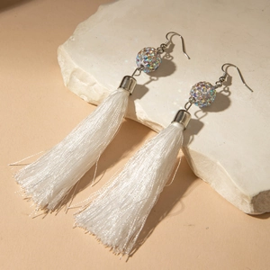 Gros plan sur de longues boucles d'oreilles à franges blanches et strass nacrés