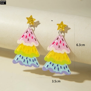 Gros plan de boucles d'oreilles sapin de Noël en acrylique coloré avec étoiles dorées