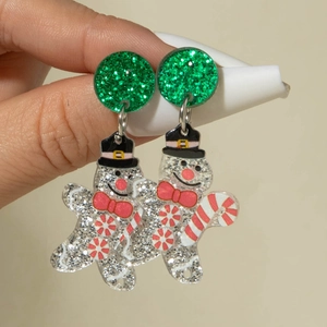 Détail de boucles d'oreilles bonhomme de neige en acrylique scintillant avec motifs