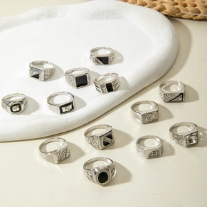 Detailed view of 12 vintage silver rings with black enamel and crystal on a ceramic tray
