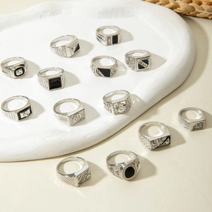 Detailed view of a 13-piece silver-tone ring set with rhinestones on a white plaster tray