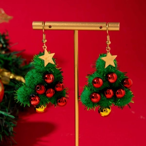 Christmas tree earrings with green faux fur balls and golden star on a display stand