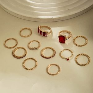 11-piece vintage gold ring set featuring red crystals and pink rhinestones on beige surface