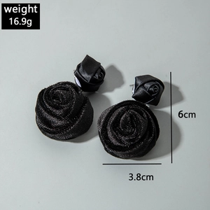 Detail of 3D black fabric rose earrings showing satin texture and layered petals structure
