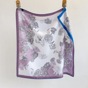 Carré de soie élégant à motif floral violet et bordure bleue suspendu sur un mur blanc