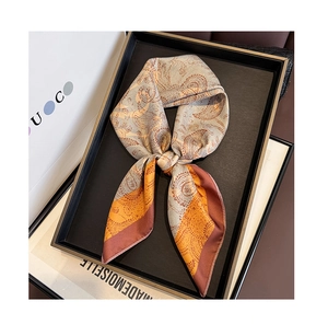 Detail of paisley print silk scarf with orange and brown tones on a minimalist tray
