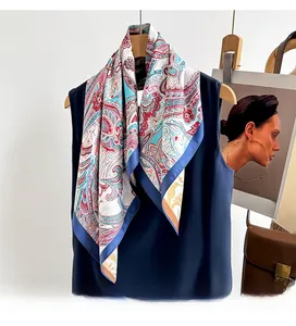 Detail of twill silk scarf with paisley patterns draped over navy blue apparel