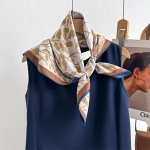 Elegant square silk scarf with floral paisley patterns in gold and navy on a blue top