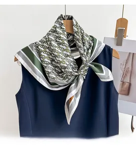 Detail of premium twill silk scarf with green and gold chain pattern tied on a neckline