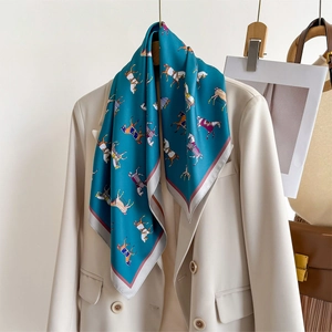 Elegant navy blue horse print silk scarf styled on a beige blazer for women