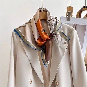 Foulard en soie élégant avec blocs de couleur orange et carreaux sur tailleur beige