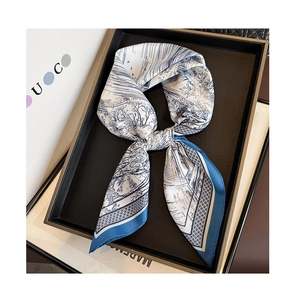 Detailed view of a blue landscape printed silk scarf tied on a minimalist black display tray