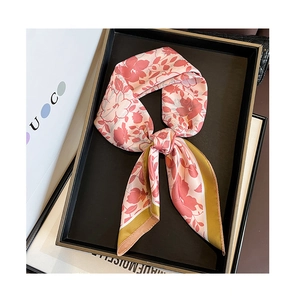 Detail of silk scarf with pink floral patterns and olive green borders on display tray