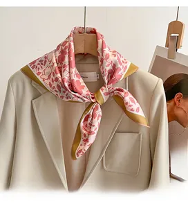 Pink floral silk scarf with olive green border styled on a beige suit lapel