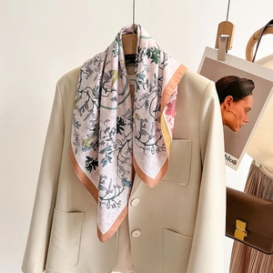 Floral silk scarf in pastel pink with green botanical prints styled on a beige blazer
