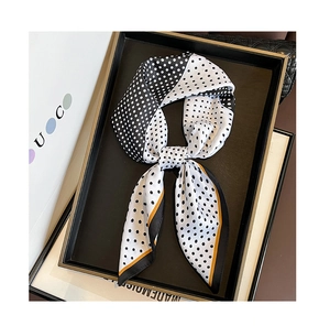 Detail of silk scarf with black polka dots, yellow borders and elegant bow knot tie