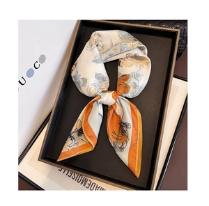 Detailed view of floral satin silk scarf with vintage orange print on a display tray